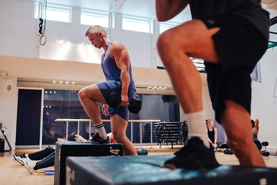 Man gör step-ups med hantel på gymmet.