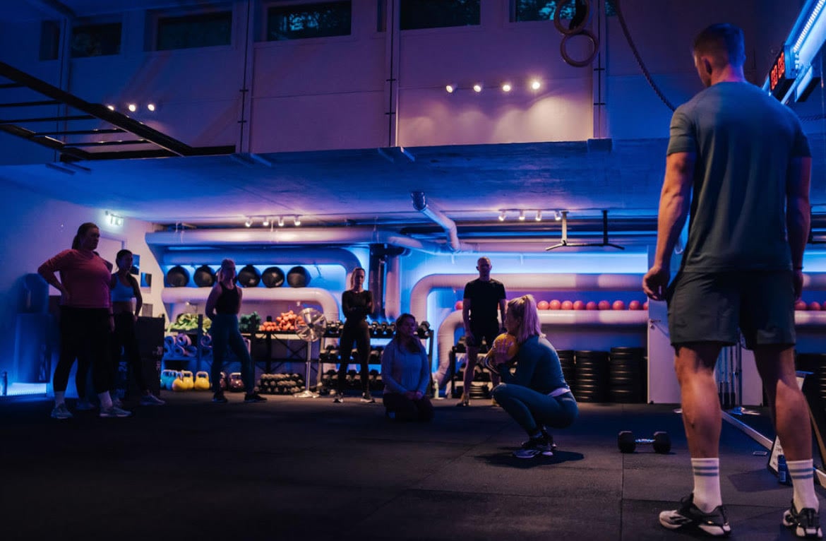 Gruppträning på gym i Östermalm med blå belysning.